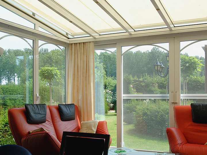conservatory awning mounted flat over a sunroom with curtains open and red and black furniture